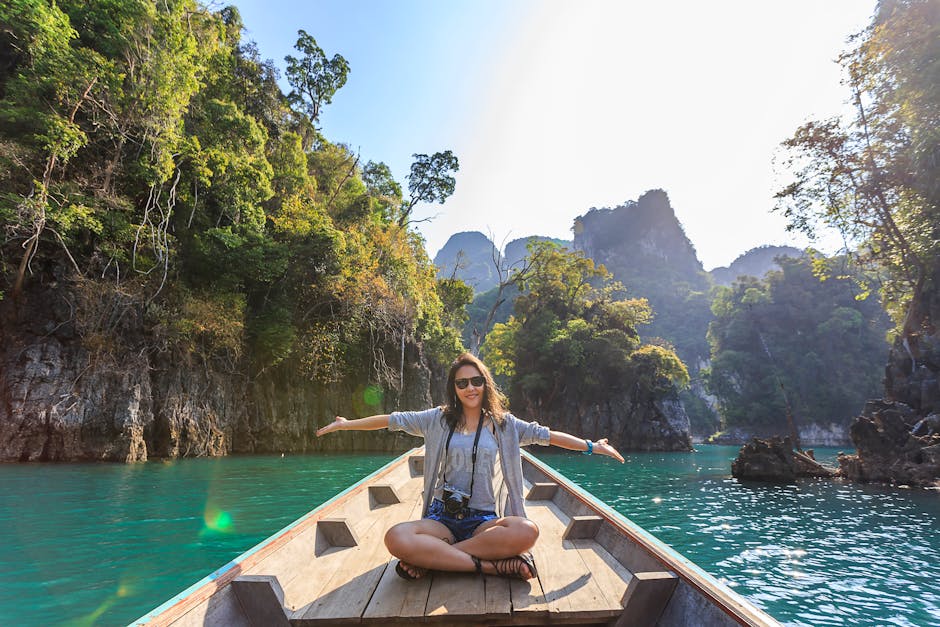 Asian woman relishing a serene boat journey through the lush karst landscape of Thailand's Khlong Sok. next to her AirBnb stay.
